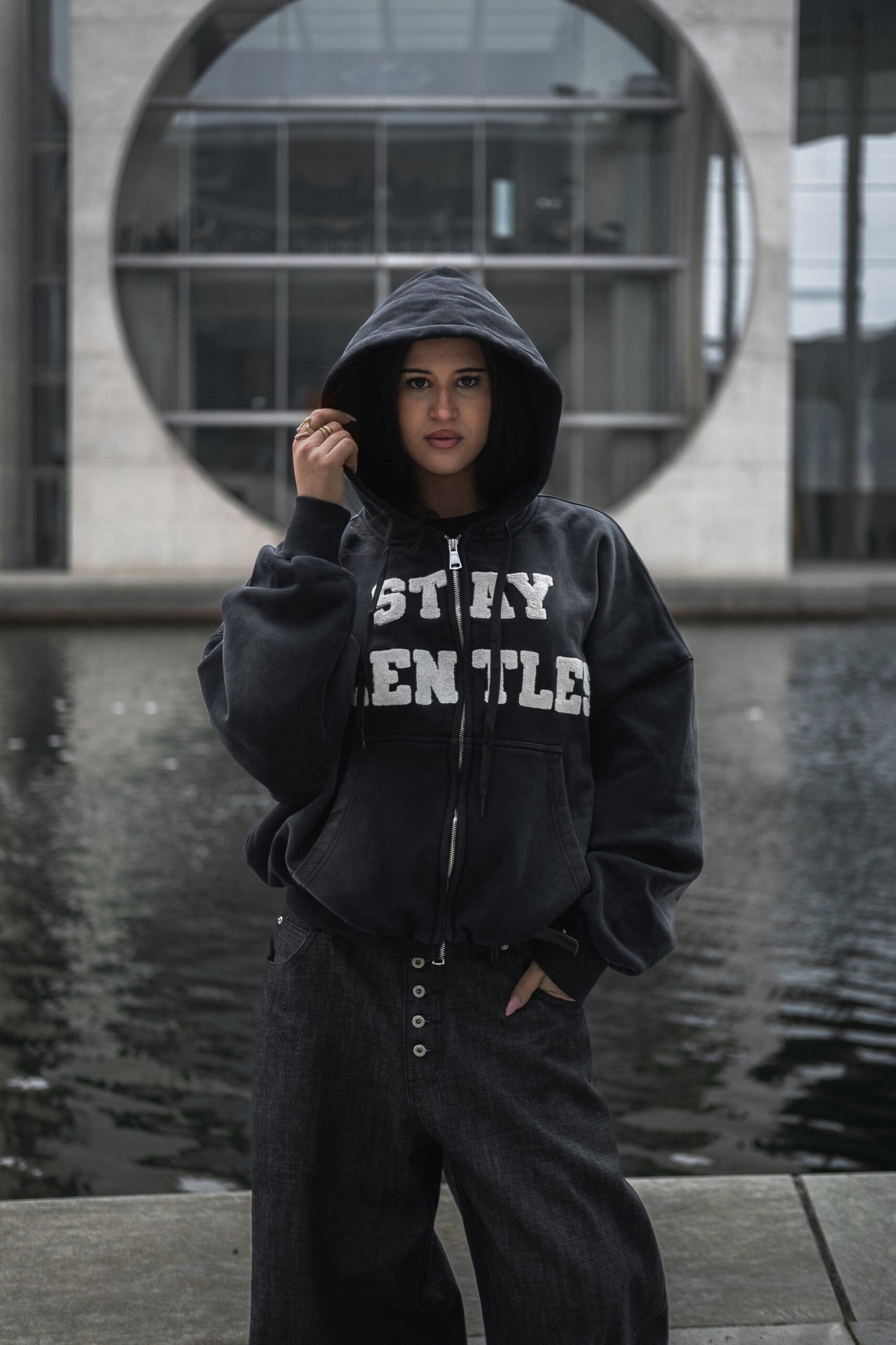 Person in oversized hoodie by water